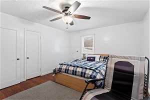 Bedroom with dark hardwood / wood-style floors, ceiling fan, and a textured ceiling