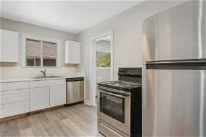 Kitchen featuring stainless steel appliances, white cabinetry, sink, and LVP flooring