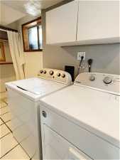 Washroom with electric dryer hookup, washer and dryer, and light tile floors