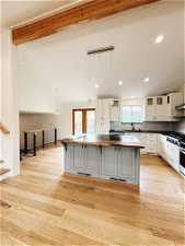 Kitchen with decorative light fixtures, light hardwood / wood-style flooring, tasteful backsplash, and white cabinetry