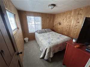 Carpeted bedroom featuring wood walls