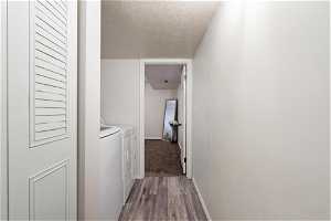 Hallway featuring a textured ceiling, separate washer and dryer, and hardwood / wood-style floors