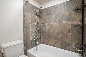 Bathroom with tiled shower / bath and toilet
