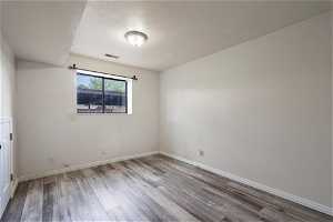 Unfurnished room with a textured ceiling and hardwood / wood-style floors