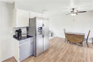 Kitchen with white cabinetry, light hardwood / wood-style floors, ceiling fan, and stainless steel fridge