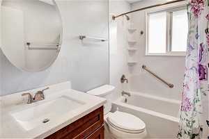 Full bathroom with vanity, shower / bathtub combination with curtain, and toilet