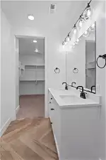 Bathroom with vanity with extensive cabinet space, double sink, and parquet flooring