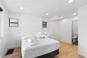 Bedroom with light hardwood / wood-style floors and connected bathroom