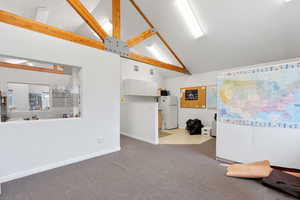 Interior space with high vaulted ceiling, light colored carpet, and beam ceiling