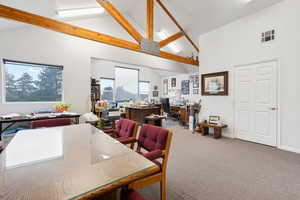 Carpeted dining room featuring beamed ceiling and high vaulted ceiling