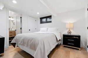 Bedroom with beamed ceiling and light hardwood / wood-style floors