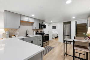 Kitchen featuring gray cabinets, light hardwood / wood-style flooring, stainless steel appliances, and sink