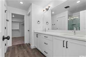 Bathroom featuring hardwood / wood-style floors, double vanity, and a shower with shower door