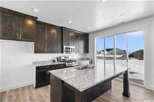 Kitchen featuring light hardwood / wood-style flooring, sink, stainless steel appliances, and a center island with sink