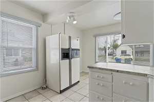 Kitchen featuring white cabinets, fridge with ice dispenser, and light tile floors