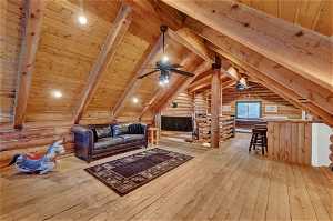 Bonus room featuring wood ceiling, light hardwood / wood-style flooring, lofted ceiling with beams, and rustic walls