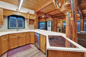 Kitchen with beamed ceiling, sink, tasteful backsplash, and log walls