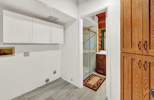 Laundry area with washer hookup, hookup for an electric dryer, cabinets, and light hardwood / wood-style floors