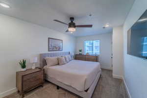 Bedroom featuring ceiling fan, carpet, and a textured ceiling