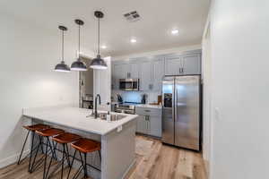 Kitchen featuring kitchen peninsula, appliances with stainless steel finishes, sink, and light wood-type flooring