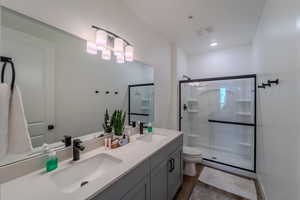 Bathroom with walk in shower, dual vanity, and toilet