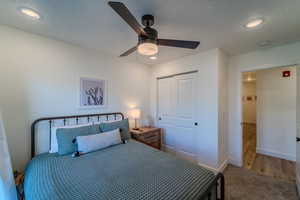 Bedroom with a closet, a textured ceiling, hardwood / wood-style floors, and ceiling fan