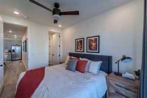 Bedroom with ceiling fan, stainless steel fridge, and light wood-type flooring