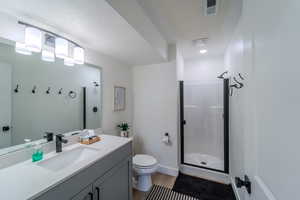 Bathroom featuring wood-type flooring, toilet, large vanity, and a textured ceiling