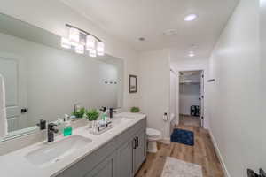 Bathroom with hardwood / wood-style floors, dual bowl vanity, and toilet