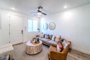 Living room with wood-type flooring, ceiling fan, and a textured ceiling