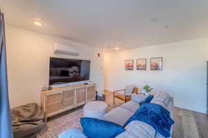 Living room featuring wood-type flooring and an AC wall unit