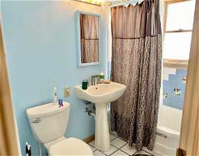 Bathroom featuring toilet, tile floors, and shower / bath combo with shower curtain