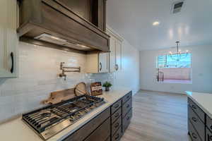 Kitchen with white cabinetry, tasteful backsplash, light hardwood / wood-style flooring, and pendant lighting