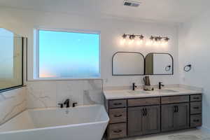 Bathroom with tile patterned flooring, a tub, and vanity