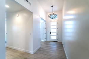 Entrance foyer featuring light hardwood / wood-style flooring and an inviting chandelier