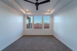 Carpeted empty room with a tray ceiling and ceiling fan