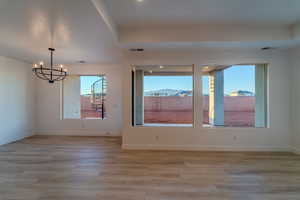 Empty room with an inviting chandelier and light wood-type flooring