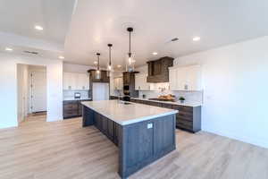 Kitchen featuring white cabinets, sink, backsplash, and light hardwood / wood-style flooring