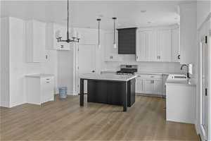 Kitchen featuring stainless steel gas range, light hardwood / wood-style flooring, pendant lighting, and sink