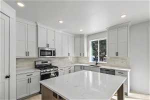 Kitchen with white cabinets, tasteful backsplash, stainless steel appliances, and sink