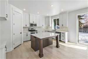 Kitchen featuring light hardwood / wood-style flooring, stainless steel appliances, white cabinets, and sink