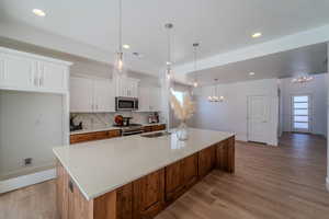 Kitchen with light hardwood / wood-style floors, a large island, backsplash, and stainless steel appliances