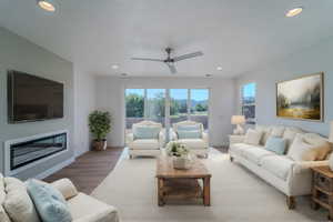 Living room with a textured ceiling, ceiling fan, and hardwood / wood-style floors