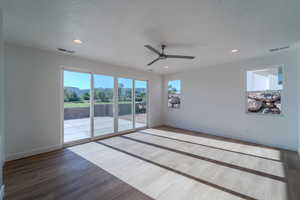 Empty room featuring wood-type flooring, a textured ceiling, and ceiling fan