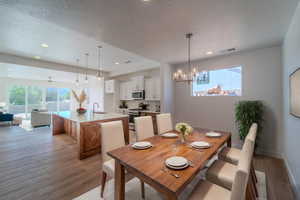 Dining area featuring sink, a textured ceiling, a chandelier, and light hardwood / wood-style floors