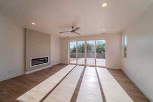 Unfurnished living room with light hardwood / wood-style flooring, a textured ceiling, and ceiling fan