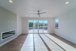 Unfurnished living room featuring hardwood / wood-style flooring, a healthy amount of sunlight, a textured ceiling, and ceiling fan