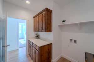 Clothes washing area featuring cabinets, light wood-type flooring, and washer hookup