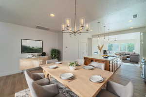 Dining space featuring hardwood / wood-style flooring, sink, a chandelier, and a textured ceiling