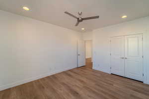 Unfurnished bedroom with ceiling fan, hardwood / wood-style floors, and a closet